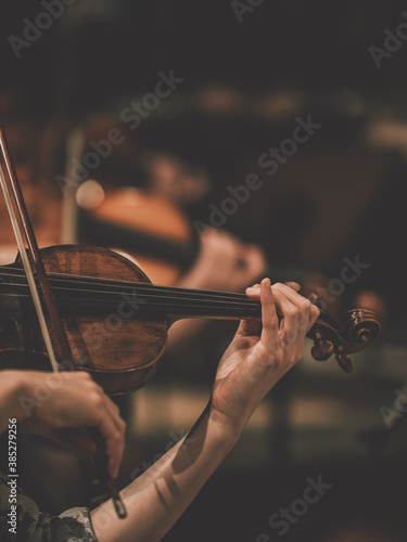 Close frame for the hand of a violinist of a symphony orchestra.
