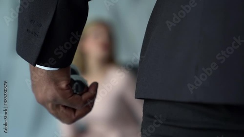 close-up of a male hand with dark skin. the man is fingering metal balls. in the background you can see a female figure in a light dress out of focus