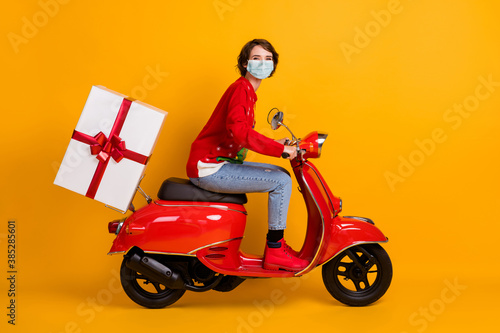 Full length profile photo of positive girl drive red motor bike deliver x-mas gift box wear mask jumper isolated color background © deagreez