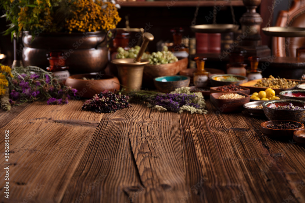 Natural medicine theme. Assorted dry herbs in bowls and brass mortar on rustic wooden table.