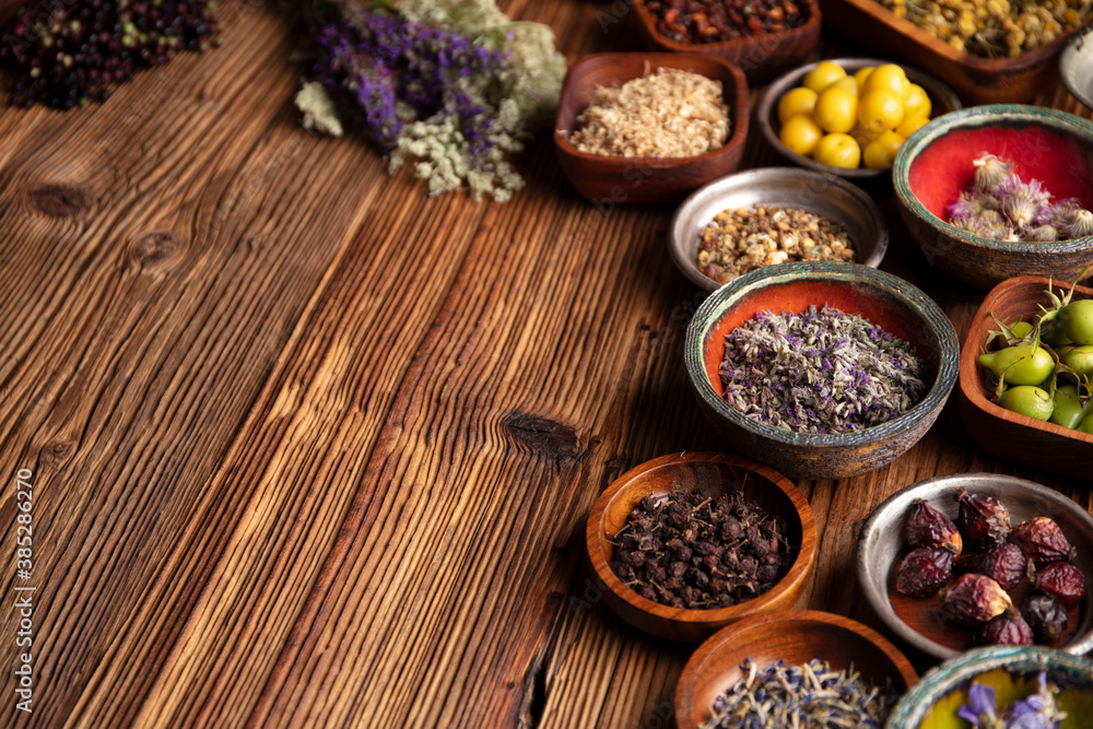 Natural medicine theme. Assorted dry herbs in bowls and brass mortar on rustic wooden table. Natural medicine theme. Assorted dry herbs in bowls and brass mortar on rustic wooden table.