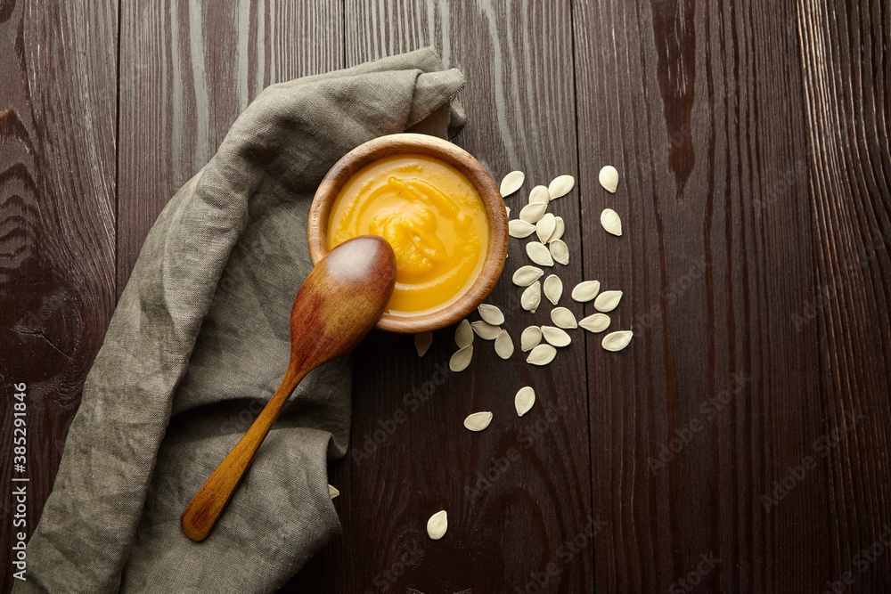 Homemade pumpkin soup with pumpkin seeds in wooden bowl Homemade pumpkin soup with pumpkin seeds in wooden bowl