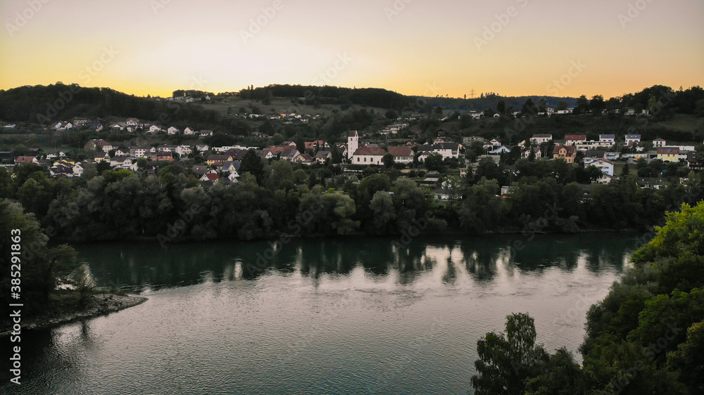 Aerial view over Aare river, to the church and residential area of Umiken and Riniken, Switzerland at sunset.
