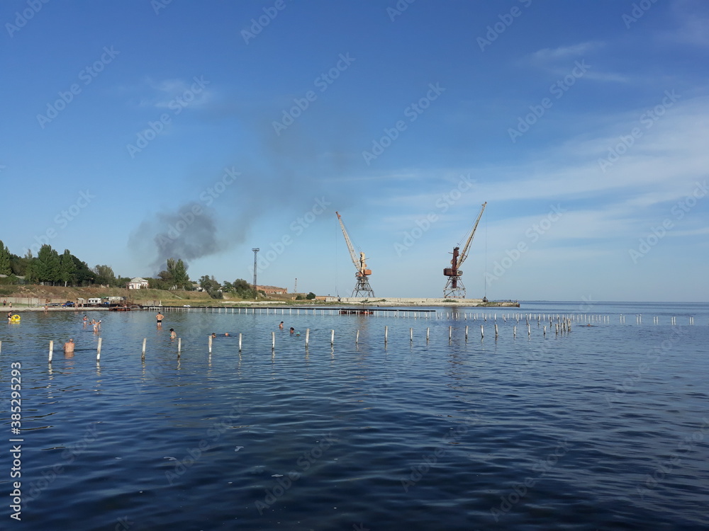 Construction works. Two cranes by the sea.