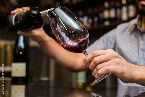 Waiter pouring red wine in a glass at restaurant.