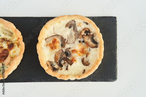 Tart with mushrooms and cheese on a white plate. Close-up