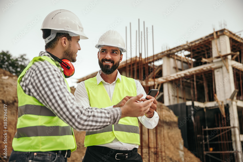 Male builders using smartphone during work Male builders using smartphone during work