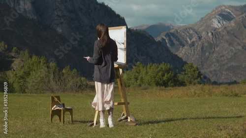 Wallpaper Mural Beautiful girl paints a picture in the mountains. A professional artist creates a landscape on a molbert. Hobbies, hobbies and work in the fresh air. Torontodigital.ca