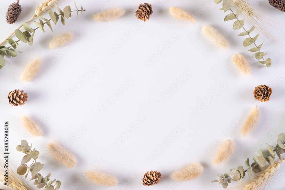 Autumn, fall concept. Frame made of eucalyptus branches, dried leaves on white background. Flat lay, top view, copy space
