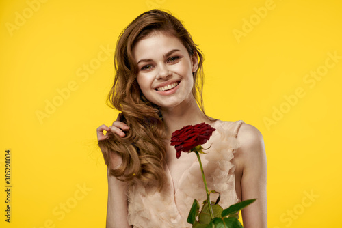 Romantic woman in evening dress with red rose on yellow background cropped view portrait