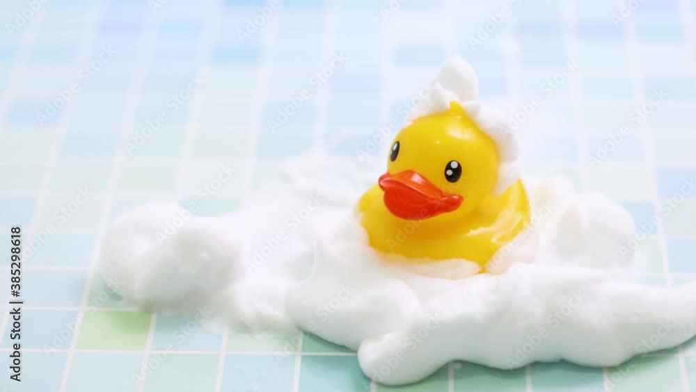 A toy duck covered in foam taking a bath A toy duck covered in foam taking a bath
