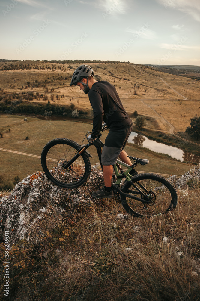 Male cyclist riding bike on rock in hills