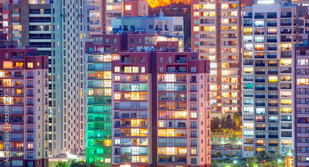 Night view of exterior apartment colorful building. High rise skyscraper with  lights in windows 