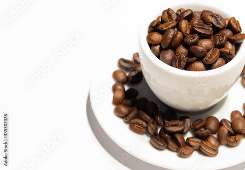 Cup with roasted coffee beans on white background. Copy space 