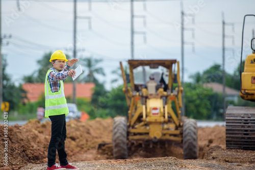 Asian engineers watch road rebuilding and inspect the construction of the road at the construction site.
