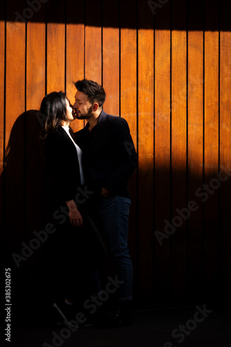 pareja de novios bogotanos en una puerta de madera con alto contraste dandose un beso  photo