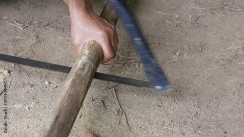 Active senior woman hands using bow saw cutting bamboo stick for craftwork woodworking at home ground.