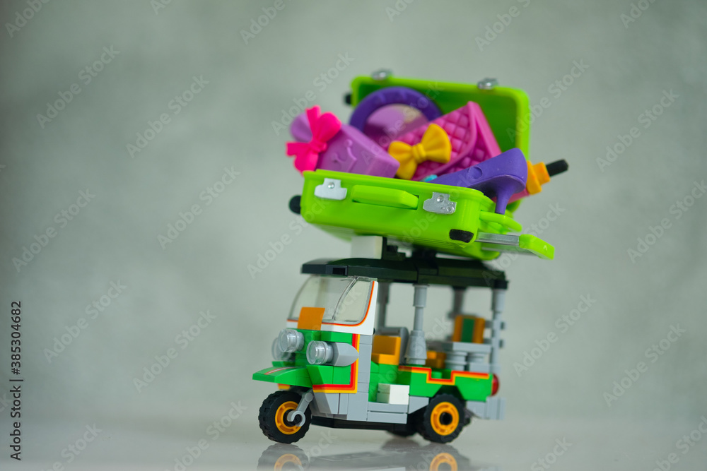 Obraz premium Miniature green suitcase and women accessories inside on top Tuk tuk car