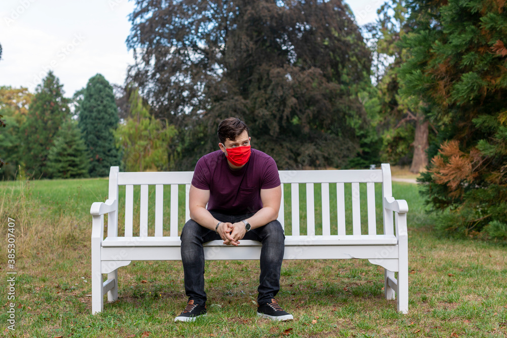 Mann mit Roter Maske sitzend auf Bank