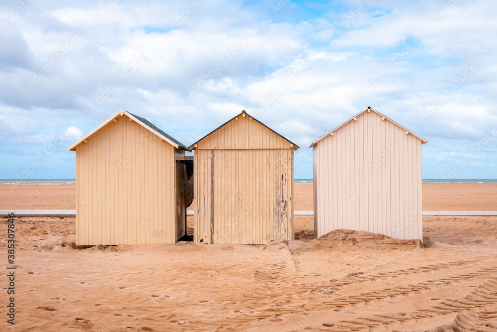 Three beach huts at the coast of Ouistreham, France, with blue sky with clouds Three beach huts at the coast of Ouistreham, France, with blue sky with clouds