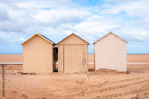Three beach huts at the coast of Ouistreham, France, with blue sky with clouds © Lizzy Komen