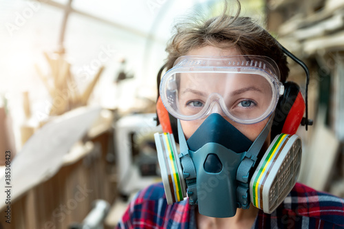 Young adult caucasian mid aged professional female carpenter grinding raw wood with orbital sander tool in carpentry diy workshop. Feminine women equality concept. Women do male hobby at workbench