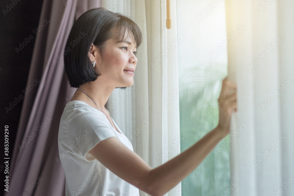 Asian woman traveler smile and looking outdoor at the room with sunlight Asian woman traveler smile and looking outdoor at the room with sunlight