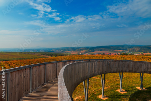 A round footbridge to the lookout tower in Kobyla in Moravia in the Czech Republic. There is a view of the countryside from the lookout tower. In the background is a blue sky with white clouds. photo