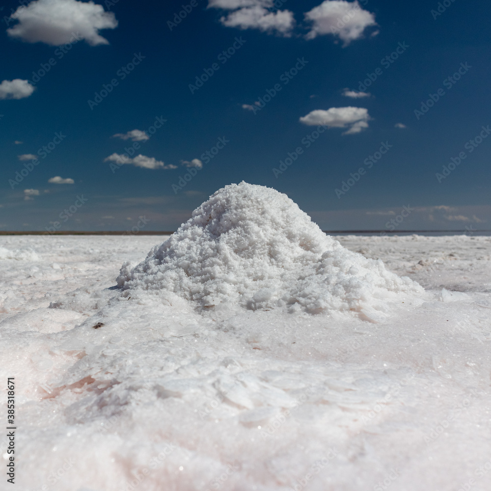 White salt bunch collecting. Close-up shining sea salt on coast of salt lake with dark blue sky background. Spa recreation White salt bunch collecting. Close-up shining sea salt on coast of salt lake with dark blue sky background. Spa recreation