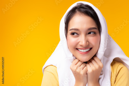 Happy young woman using sweater shirt covers her head with happiness and smile face Attractive beauty girl look at copy space, yellow background