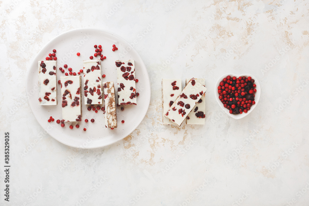 White Chocolate Cracker Toffee with cranberries and almond on plate and beside. Delicious Christmas treat. Top view, blank space White Chocolate Cracker Toffee with cranberries and almond on plate and beside. Delicious Christmas treat. Top view, blank space
