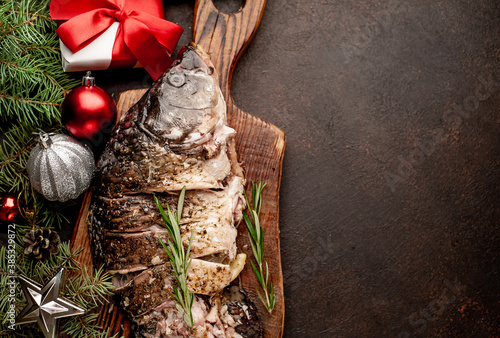 baked carp for the holiday of Christmas on a stone background with Christmas trees and Christmas tree decorations with copy space for your text