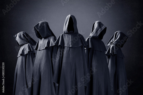 Group of five scary figures in hooded cloaks in the dark photo