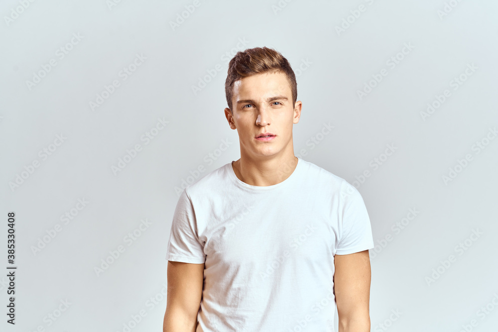 Handsome man in a white T-shirt on a light background close-up portrait cropped view Handsome man in a white T-shirt on a light background close-up portrait cropped view