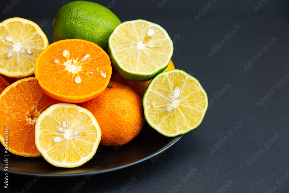 Citrus. Lemons, limes and tangerines whole and halves on black plates on a black background. Healthy food and vitamins Citrus. Lemons, limes and tangerines whole and halves on black plates on a black background. Healthy food and vitamins