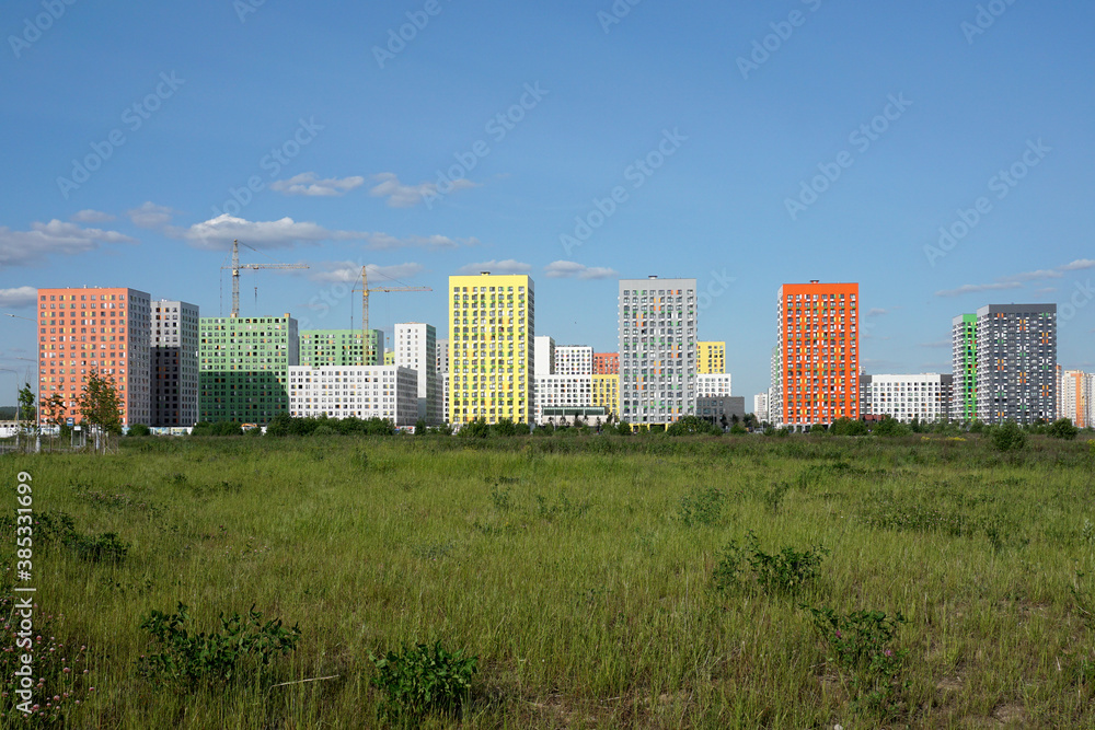 New homes, young city in a green field against a blue sky.