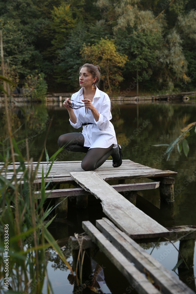 Woman in white shirt sitting near the lake Woman in white shirt sitting near the lake