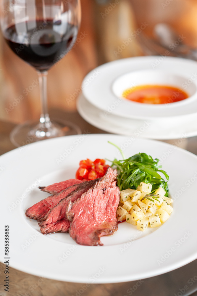 プレートに乗った肉料理と、付け合わせの野菜と赤ワイン プレートに乗った肉料理と、付け合わせの野菜と赤ワイン