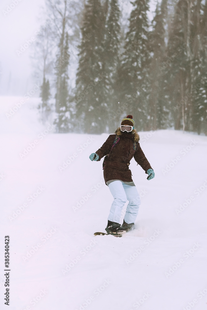 Girl a snowboarder is snowboarding in the snow blizzard.
