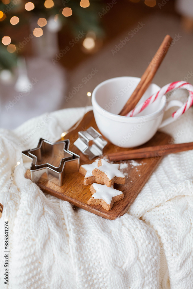 Christmas decor. Mug, Christmas candy, Christmas cookies, knitted sweater, wicker basket against the background of a Christmas tree. Cozy holidays. Christmas decor. Mug, Christmas candy, Christmas cookies, knitted sweater, wicker basket against the background of a Christmas tree. Cozy holidays.