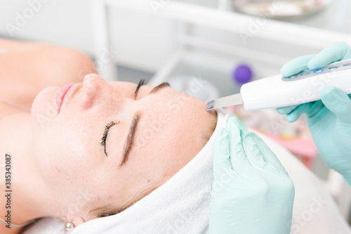 The female cosmetologist makes  a procedure of ultrasonic cleaning face  close-up. Young woman in a beauty salon. Concept of cosmetology and professional skin care