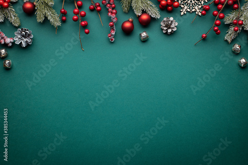 Christmas border with classic decorations. Fir branches, red balls, jingle bells on green background. photo