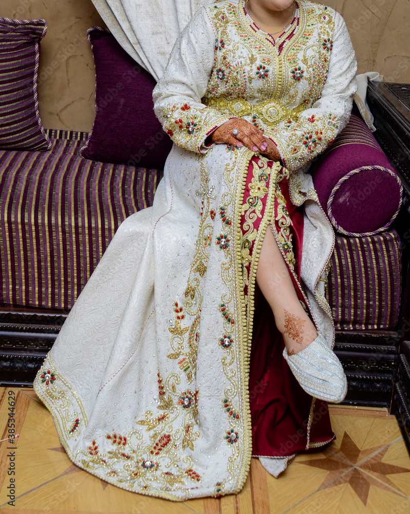 The Moroccan bride sits bug the chair wearing the Moroccan caftan