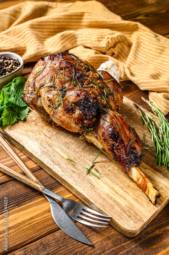 Roasted lamb, sheep leg on a cutting board with rosemary. wooden background. Top view