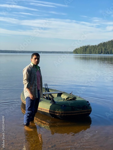 young man in an inflatable boat on the lake, resting. the man using the smartphone