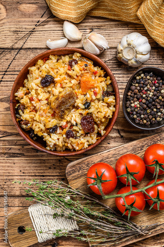 Pilaf in a wooden bowl. Central Asian cuisine Plov.  Wooden background. Top view