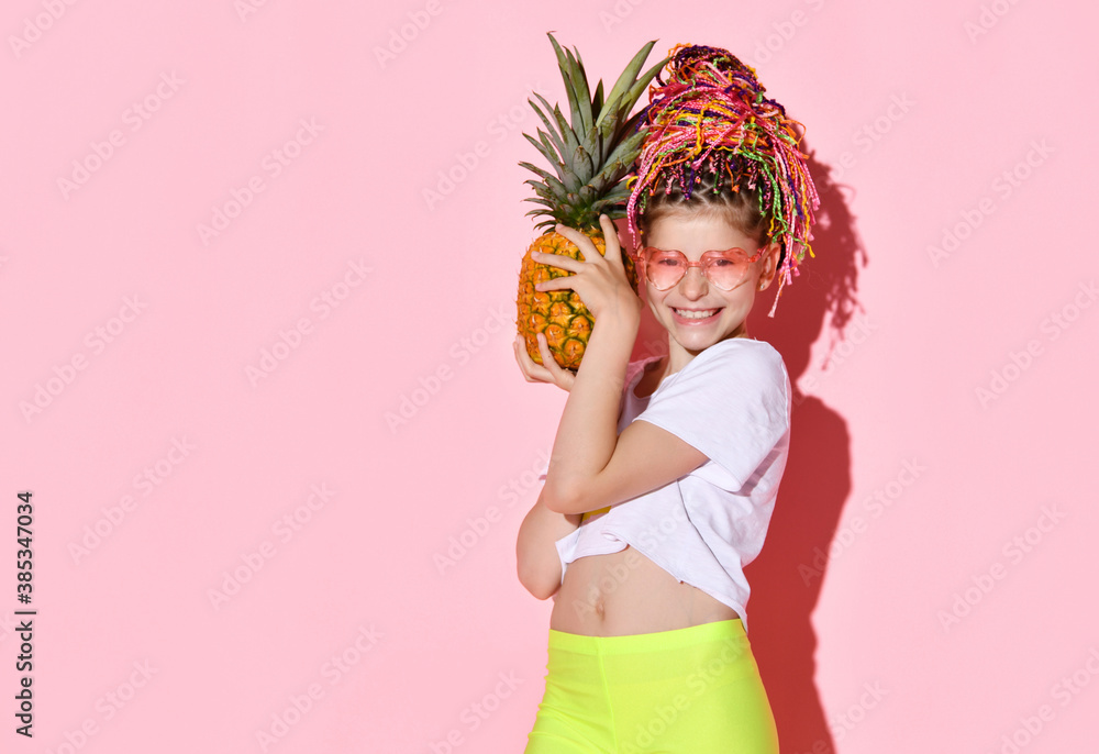 Teenage female with african pigtails, in sunglasses. She is holding pineapple and smiling, posing on pink background. Close up Teenage female with african pigtails, in sunglasses. She is holding pineapple and smiling, posing on pink background. Close up