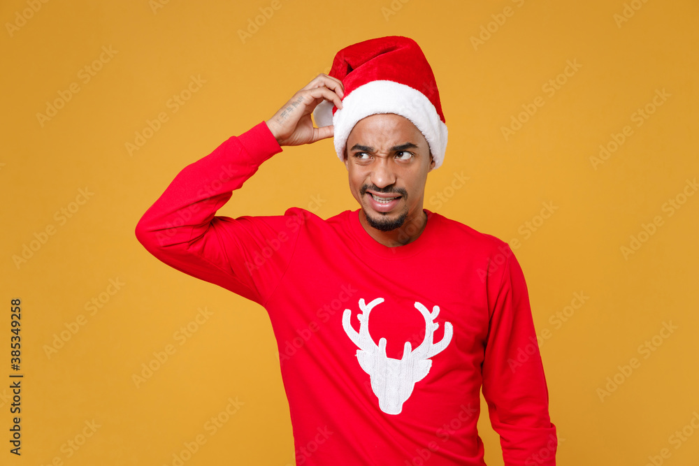 Preoccupied young Santa african american man in sweater Christmas hat put hand on head looking aside isolated on yellow background studio portrait. Happy New Year celebration merry holiday concept. Preoccupied young Santa african american man in sweater Christmas hat put hand on head looking aside isolated on yellow background studio portrait. Happy New Year celebration merry holiday concept.