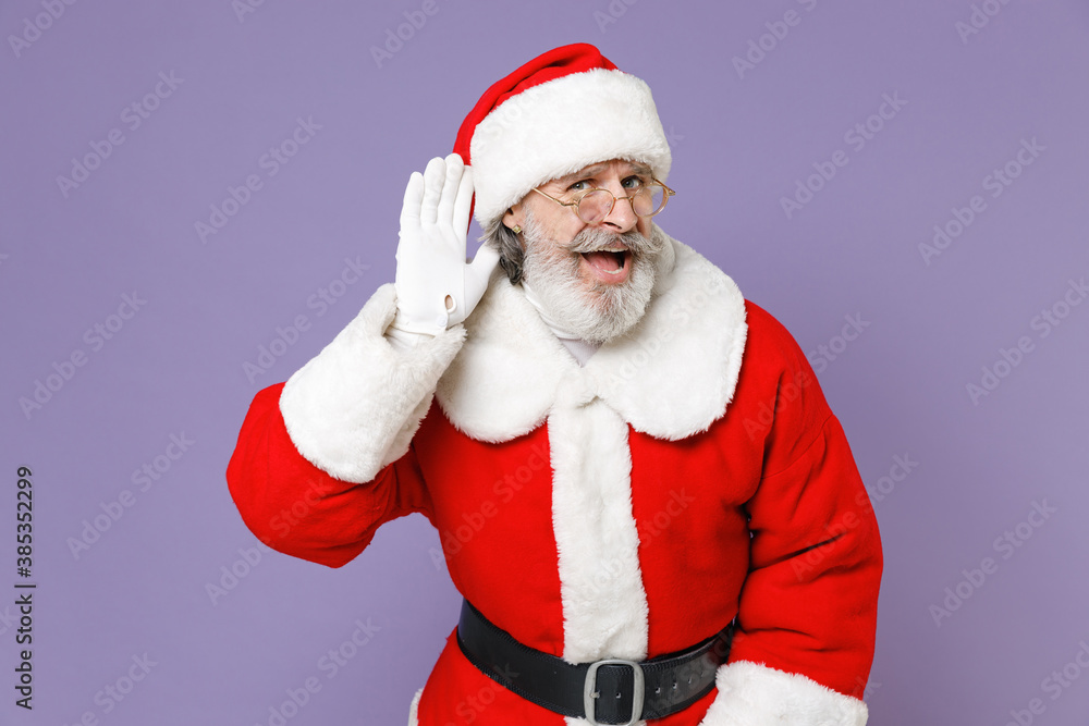 Curious Santa Claus man in Christmas hat red suit coat white gloves glasses try to hear you overhear listening intently isolated on violet background. Happy New Year celebration merry holiday concept. Curious Santa Claus man in Christmas hat red suit coat white gloves glasses try to hear you overhear listening intently isolated on violet background. Happy New Year celebration merry holiday concept.