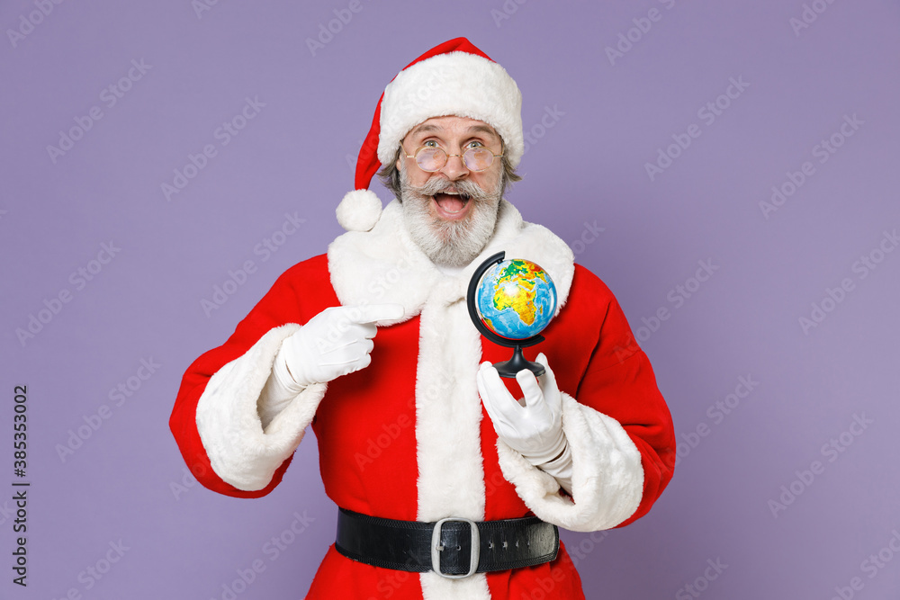 Shocked Santa Claus man in Christmas hat red suit coat gloves glasses pointing index finger on Earth world globe isolated on violet background studio. Happy New Year celebration merry holiday concept. Shocked Santa Claus man in Christmas hat red suit coat gloves glasses pointing index finger on Earth world globe isolated on violet background studio. Happy New Year celebration merry holiday concept.